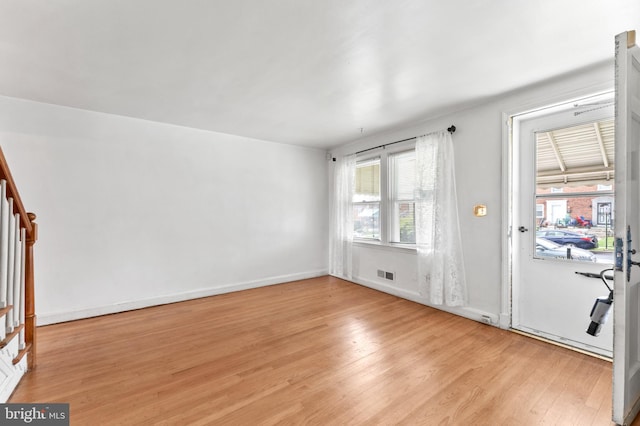 unfurnished room featuring light wood-type flooring, stairway, and baseboards