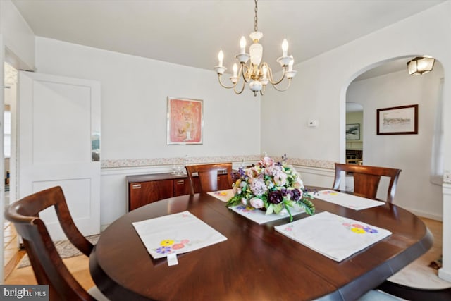dining space featuring arched walkways and a chandelier