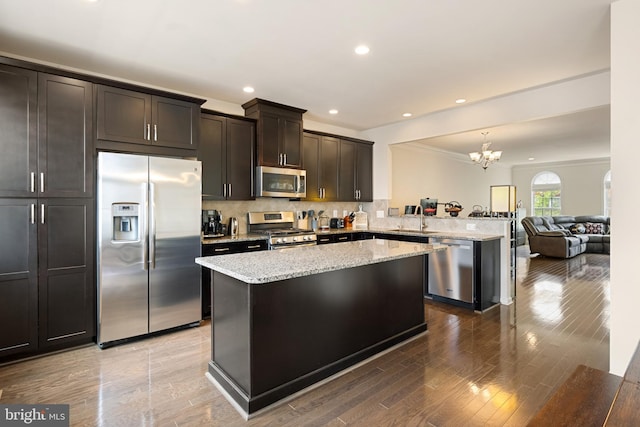 43008 Paris Gap Sq, Ashburn, VA 20148 - kitchen featuring stainless steel appliances, a sink, a peninsula, a chandelier, and crown molding