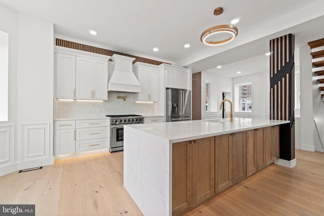 101 S Baton Rouge Ave, Ventnor City, NJ 08406 - kitchen featuring appliances with stainless steel finishes, premium range hood, light wood-type flooring, light stone counters, and white cabinetry