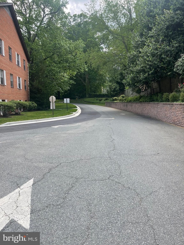 view of asphalt street with traffic signs and curbs