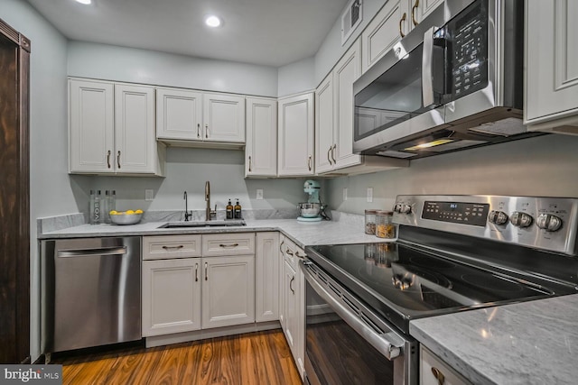 2501 Calvert St NW Unit 306, Washington, DC 20008 - kitchen featuring appliances with stainless steel finishes, a sink, dark wood-style floors, light stone counters, and white cabinets