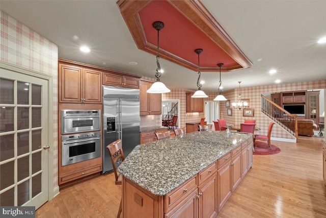 217 Rising Meadow Way E, Stroudsburg, PA 18302 - kitchen featuring stainless steel appliances, wallpapered walls, a sink, light wood finished floors, and light stone countertops