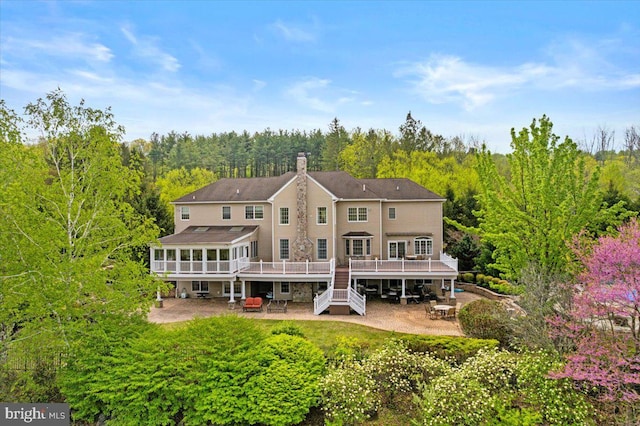 217 Rising Meadow Way E, Stroudsburg, PA 18302 - back of property with a patio area, a deck, a sunroom, a chimney, and a view of trees