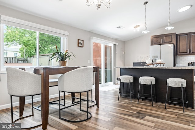 370 Juniper Ct, Herndon, VA 20170 - kitchen with white refrigerator with ice dispenser, a kitchen bar, dark brown cabinetry, wood finished floors, and lofted ceiling