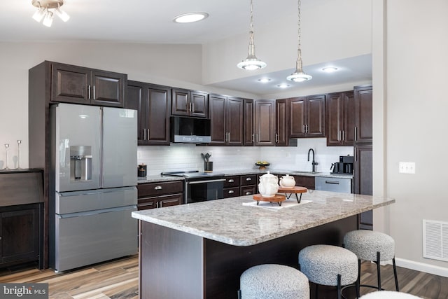 370 Juniper Ct, Herndon, VA 20170 - kitchen with stainless steel appliances, vaulted ceiling, a breakfast bar area, backsplash, and light wood finished floors