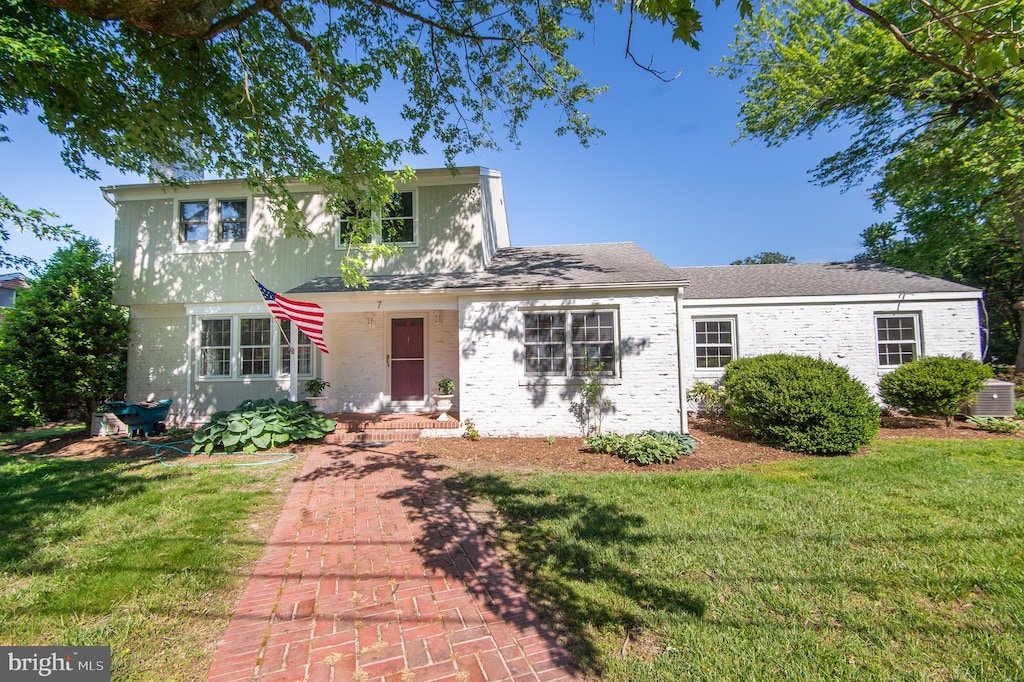 view of front of home featuring a front lawn, cooling unit, and brick siding
