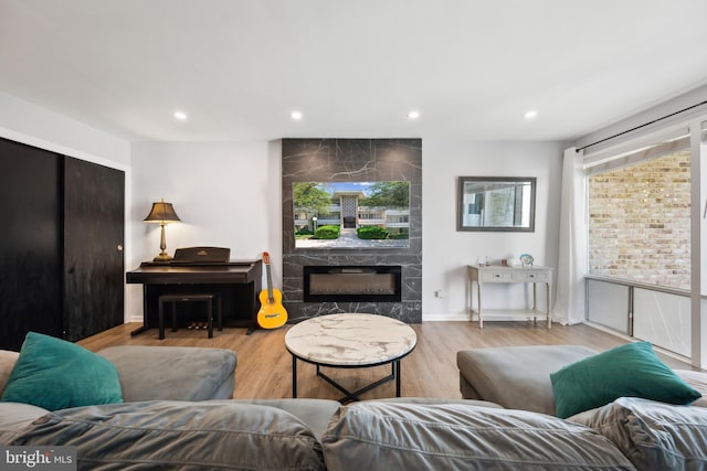 living room with a tile fireplace, recessed lighting, and wood finished floors