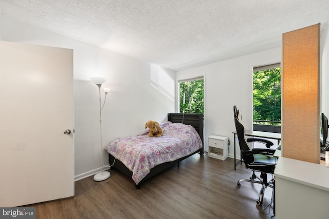 bedroom featuring wood finished floors, a desk, baseboards, and a textured ceiling