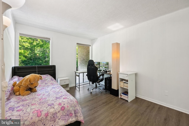 bedroom featuring dark wood finished floors, an office area, and baseboards
