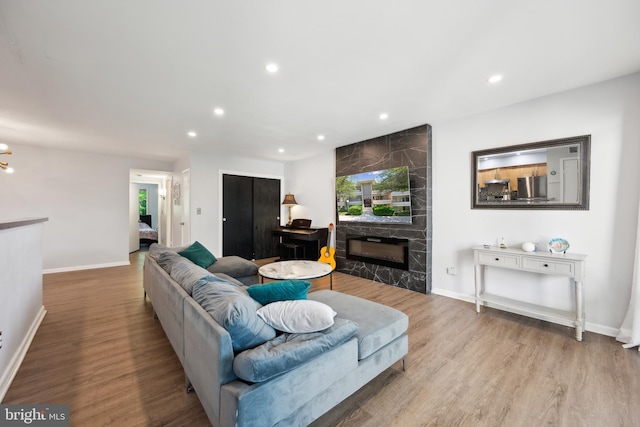 living room with a fireplace, recessed lighting, wood finished floors, and baseboards