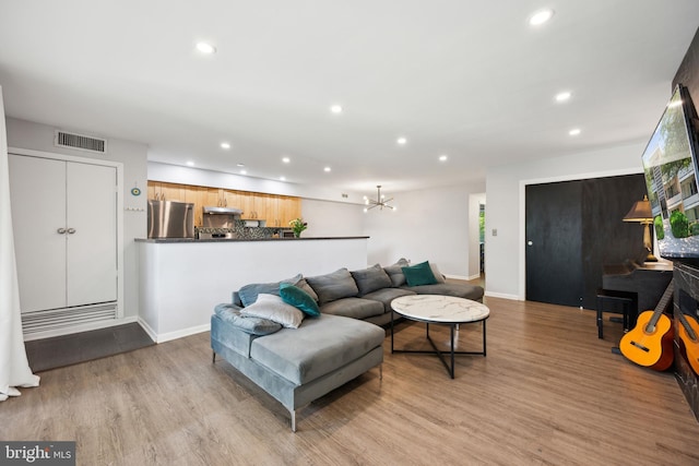 living room featuring recessed lighting, wood finished floors, baseboards, and a chandelier