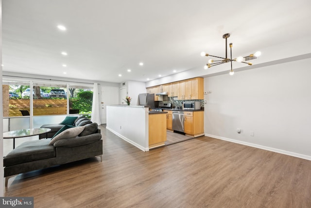kitchen with appliances with stainless steel finishes, open floor plan, a chandelier, dark countertops, and recessed lighting