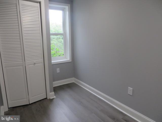 2413 Nicholas St, Philadelphia, PA 19121 - unfurnished bedroom with multiple windows, dark wood-style floors, baseboards, and a closet