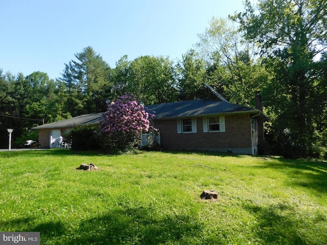 view of property exterior with brick siding, a yard, and a chimney