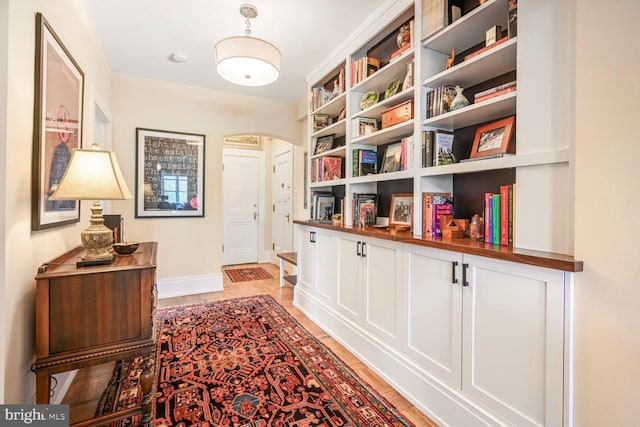 hallway with arched walkways and baseboards