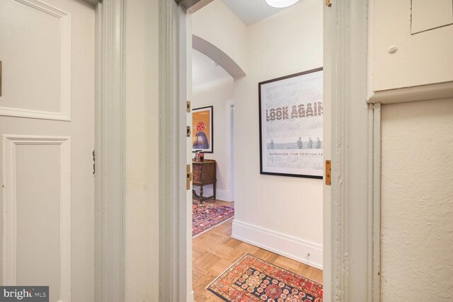corridor with arched walkways and baseboards
