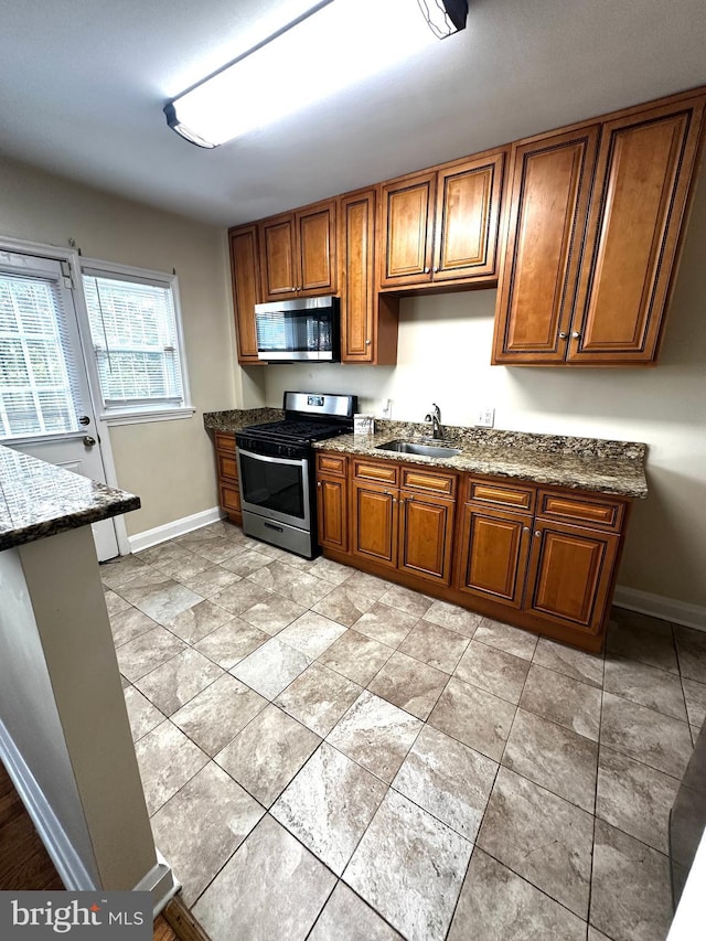912 Evesham Ave, Baltimore, MD 21212 - kitchen with appliances with stainless steel finishes, a sink, baseboards, and brown cabinetry