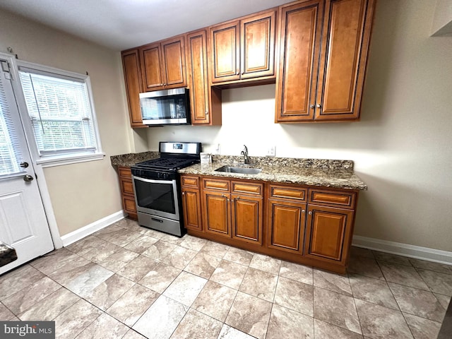 912 Evesham Ave, Baltimore, MD 21212 - kitchen featuring appliances with stainless steel finishes, baseboards, brown cabinetry, and dark stone counters