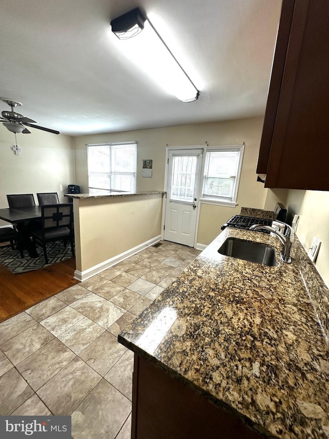 912 Evesham Ave, Baltimore, MD 21212 - kitchen with a sink, baseboards, ceiling fan, dark stone countertops, and dark brown cabinetry
