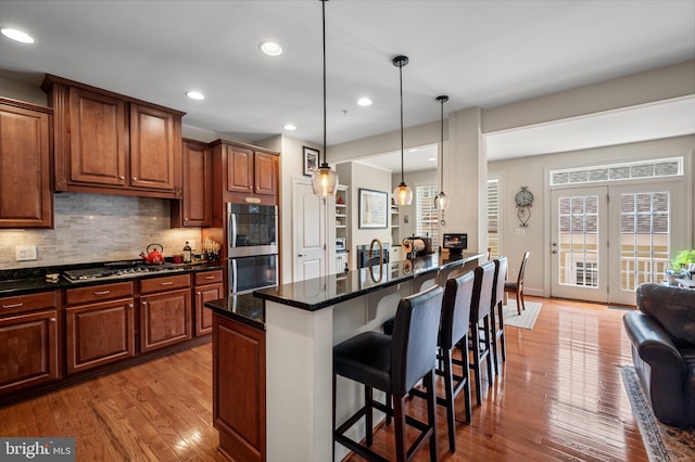 7311 Trappe St, Fulton, MD 20759 - kitchen with a kitchen bar, wood finished floors, decorative backsplash, appliances with stainless steel finishes, and decorative light fixtures
