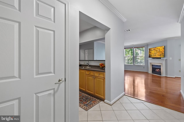 4950 Brenman Park Dr Unit 301, Alexandria, VA 22304 - bar area featuring crown molding, a sink, light tile patterned flooring, a warm lit fireplace, and baseboards
