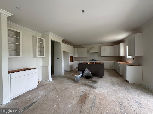 26171 Millman Dr, Hebron, MD 21830 - kitchen with a kitchen island, ornamental molding, custom range hood, glass insert cabinets, and white cabinetry