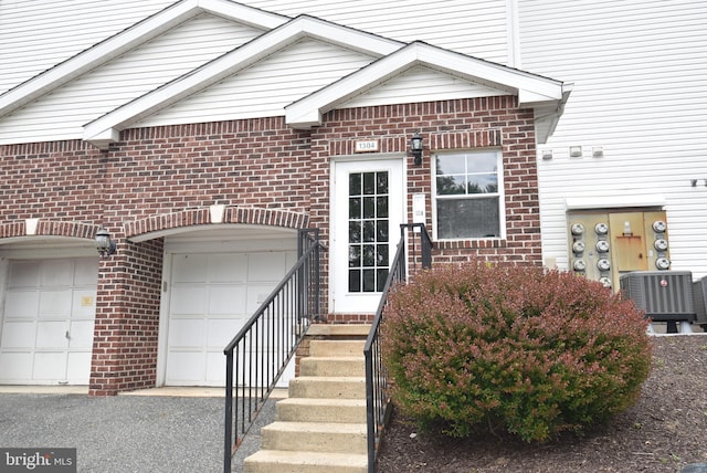 1304 Cranesbill Ct Unit 304, Belcamp, MD 21017 - view of exterior entry featuring brick siding, central AC unit, and a garage