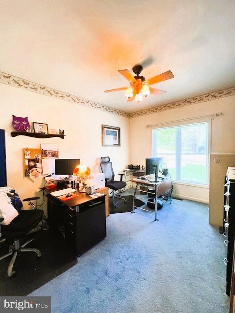 carpeted office space featuring a ceiling fan