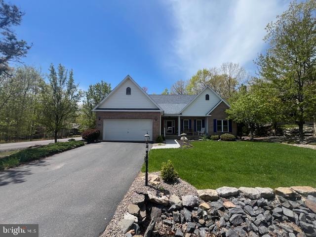 ranch-style house with driveway, an attached garage, and a front yard