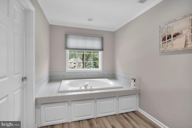 bathroom with a garden tub, ornamental molding, and wood finished floors
