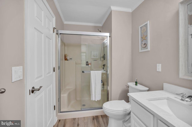 full bathroom featuring ornamental molding, a stall shower, vanity, toilet, and wood finished floors
