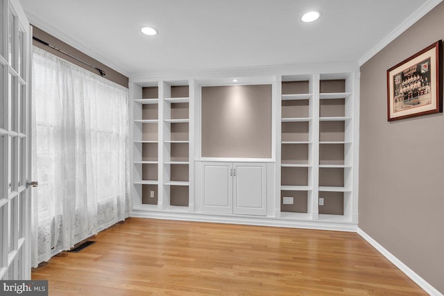 spare room featuring ornamental molding, built in shelves, light wood finished floors, baseboards, and recessed lighting