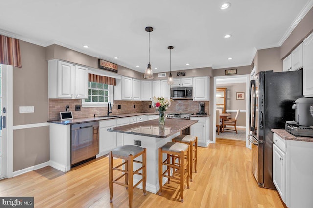 kitchen with stainless steel appliances, white cabinets, a breakfast bar area, tasteful backsplash, and light wood-style flooring