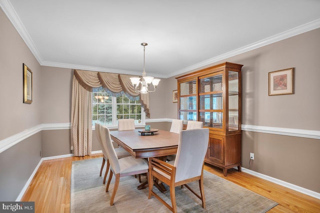 dining room with a chandelier, light wood-style floors, crown molding, and baseboards