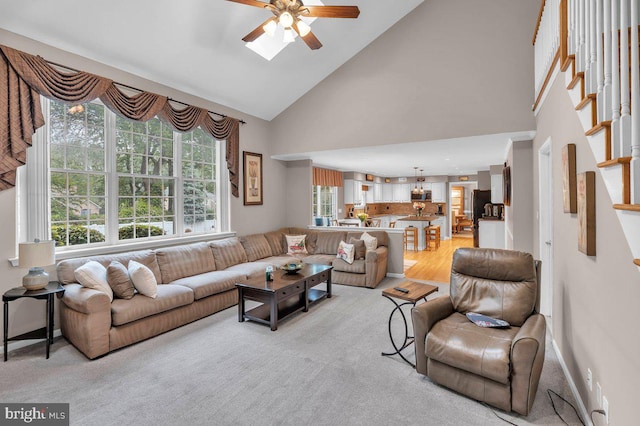 living room with a ceiling fan, high vaulted ceiling, and light wood-style floors