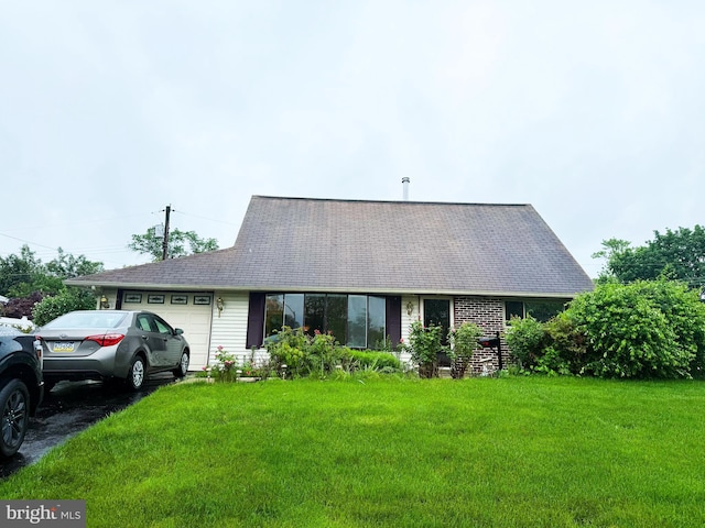 view of front of home featuring an attached garage, a front lawn, and roof with shingles