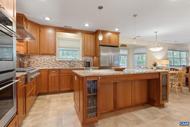 2657 Coralberry Pl, Charlottesville, VA 22911 - kitchen featuring appliances with stainless steel finishes, brown cabinetry, tasteful backsplash, a kitchen island, and recessed lighting