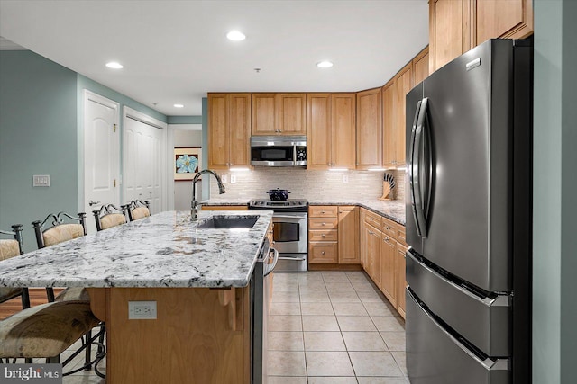 301 14th St Unit 308/309, Ocean City, MD 21842 - kitchen featuring stainless steel appliances, a sink, a kitchen bar, light tile patterned floors, and light stone countertops