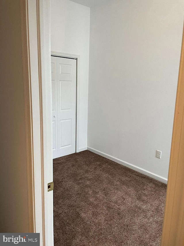 unfurnished bedroom featuring carpet floors, baseboards, and a closet