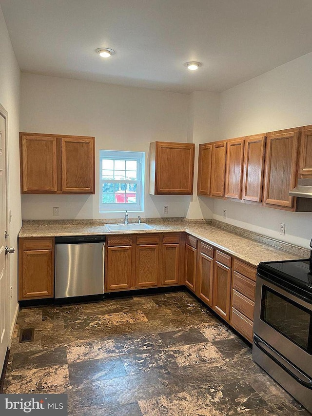 kitchen with appliances with stainless steel finishes, a sink, brown cabinetry, under cabinet range hood, and light countertops