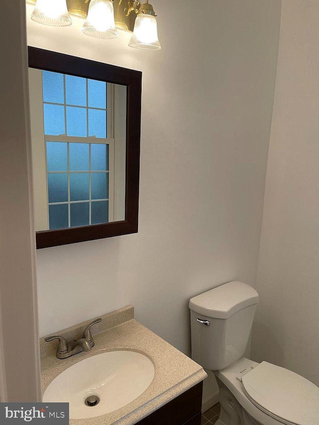 half bathroom with toilet, vanity, and tile patterned flooring