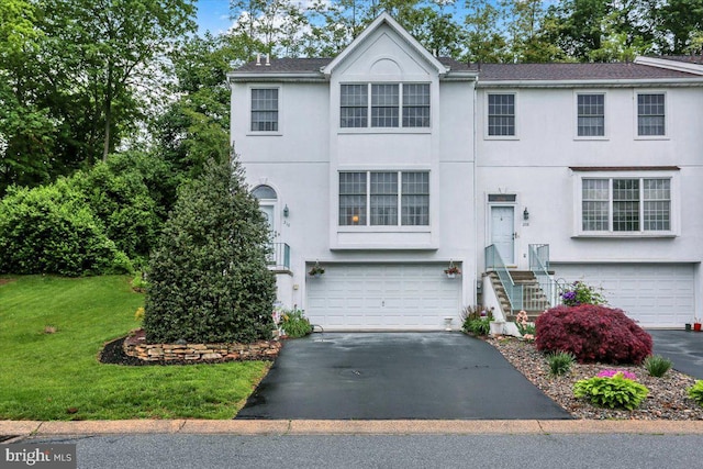 view of front of home with stucco siding, driveway, an attached garage, and a front lawn