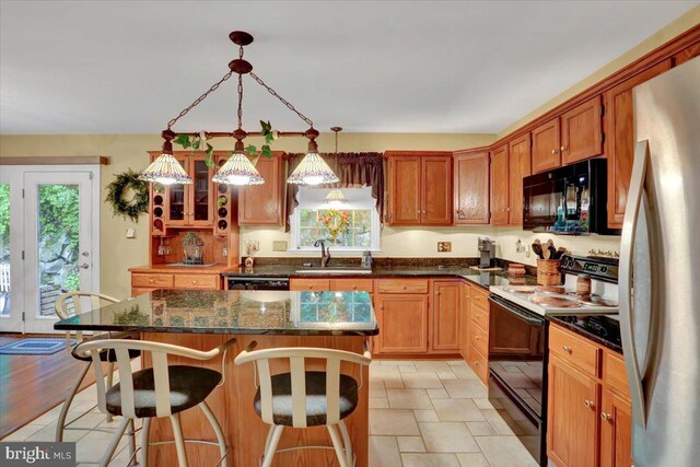 kitchen featuring freestanding refrigerator, black microwave, range with electric cooktop, a sink, and a breakfast bar