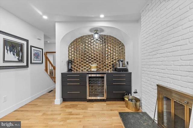 1745 Remington Dr, Crofton, MD 21114 - indoor dry bar featuring wine cooler, a brick fireplace, light wood-type flooring, stairway, and recessed lighting