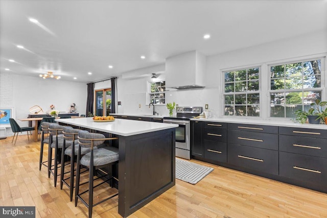 1745 Remington Dr, Crofton, MD 21114 - kitchen featuring stainless steel range with electric stovetop, wall chimney range hood, a center island, a breakfast bar area, and light countertops