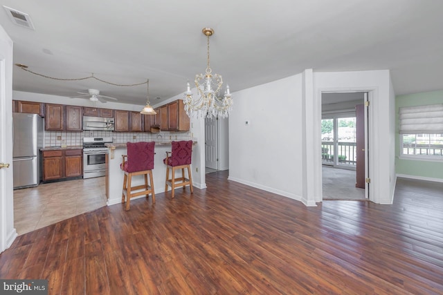 217 Pratt Ct, Sewell, NJ 08080 - kitchen with appliances with stainless steel finishes, backsplash, a breakfast bar area, wood finished floors, and open floor plan