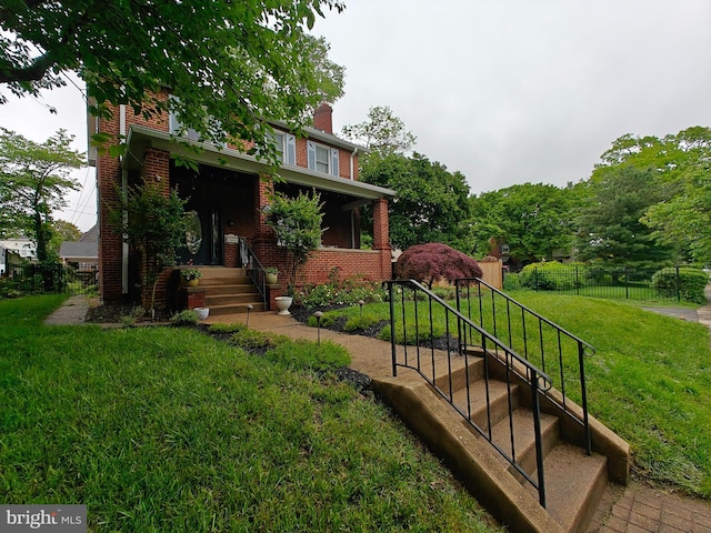view of front of house with brick siding, a chimney, and a porch