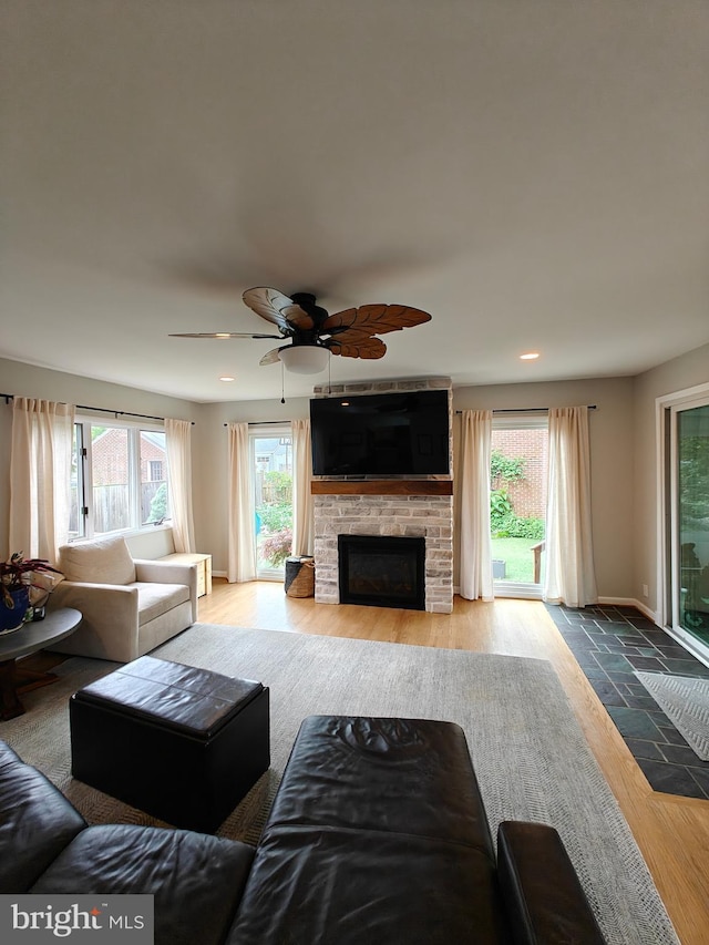 living area featuring wood finished floors, a ceiling fan, a large fireplace, recessed lighting, and baseboards
