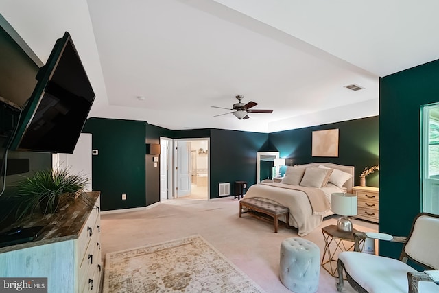 bedroom featuring light carpet, baseboards, ceiling fan, and ensuite bathroom